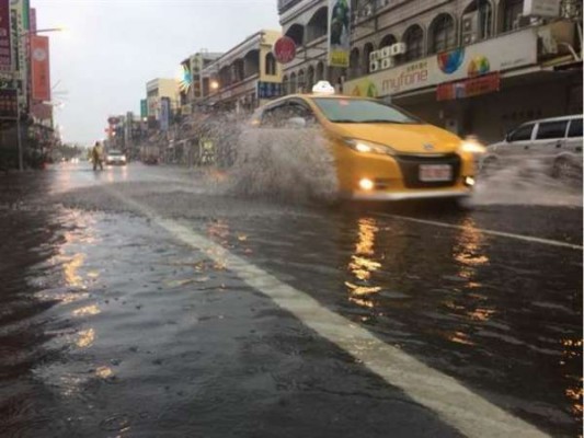 受热带性低气压影响，屏东23日大雨下不停，东港中正路一早传积水，汽车驶过都溅起大水花。（网络图）